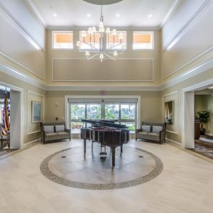 A spacious and elegant lobby featuring a grand piano and chandelier.