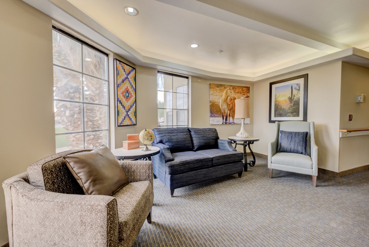A cozy living room with comfortable seating and large windows, adorned with artwork.