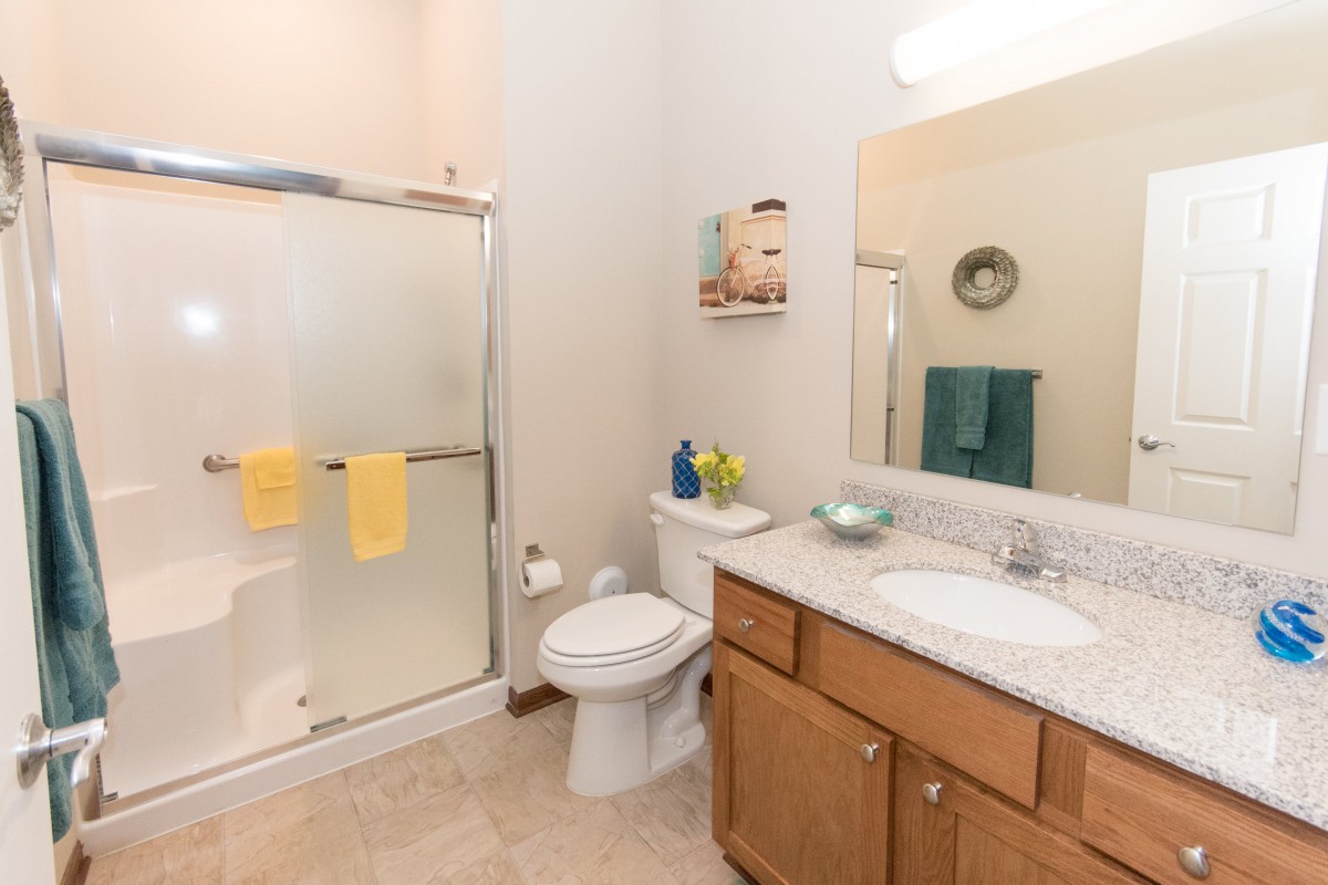 A clean bathroom with a shower, sink, and wooden cabinet.