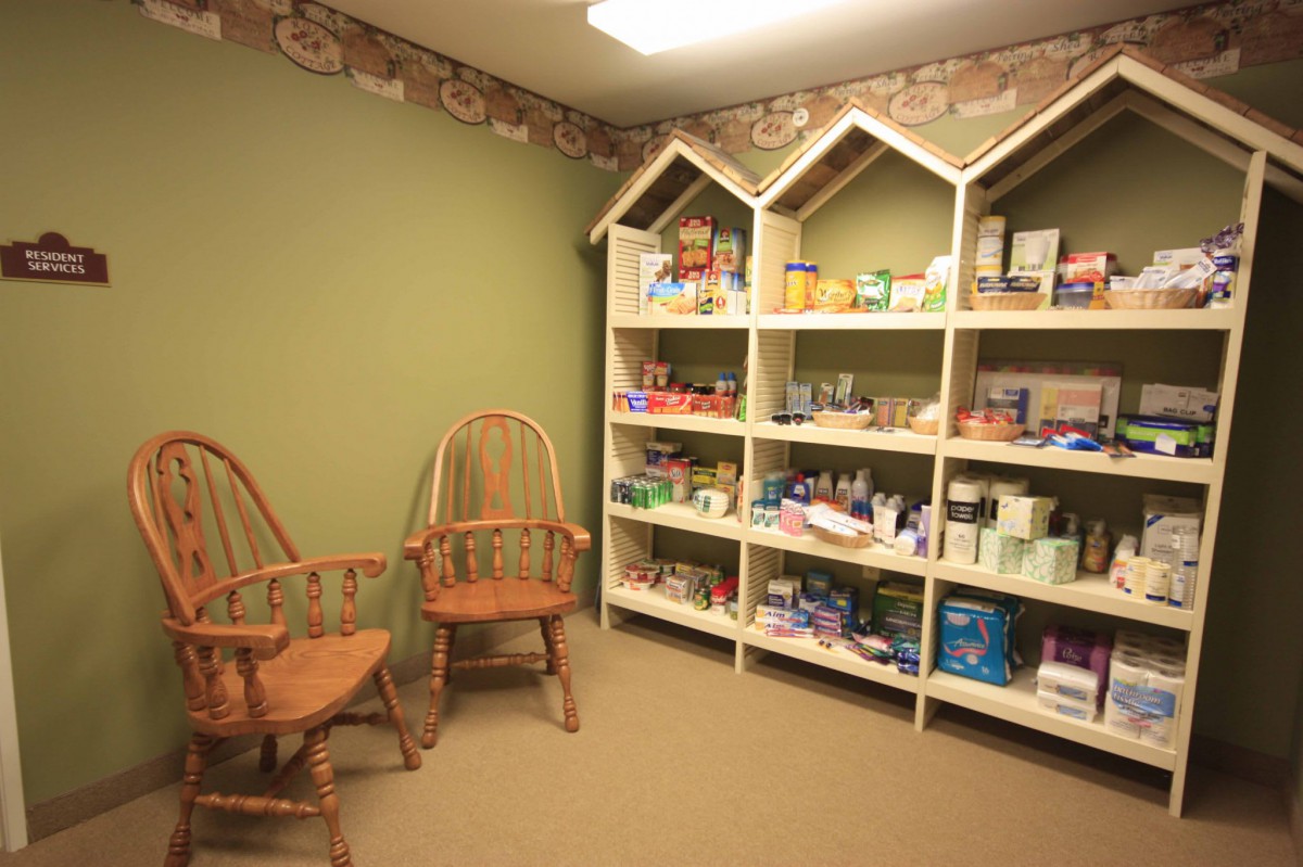 A well-organized pantry with shelves stocked with various supplies and two wooden chairs nearby.