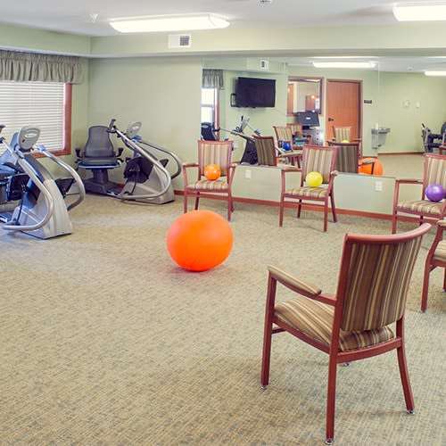 An exercise room with fitness equipment and chairs arranged around therapy balls.