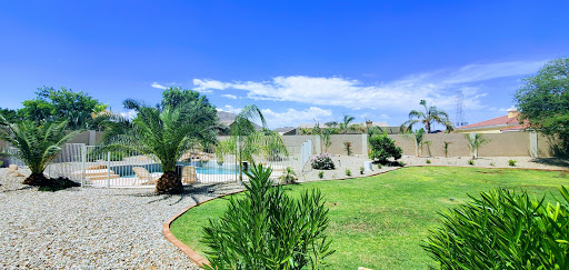 A beautiful outdoor space featuring a pool, lush greenery, and clear blue skies.