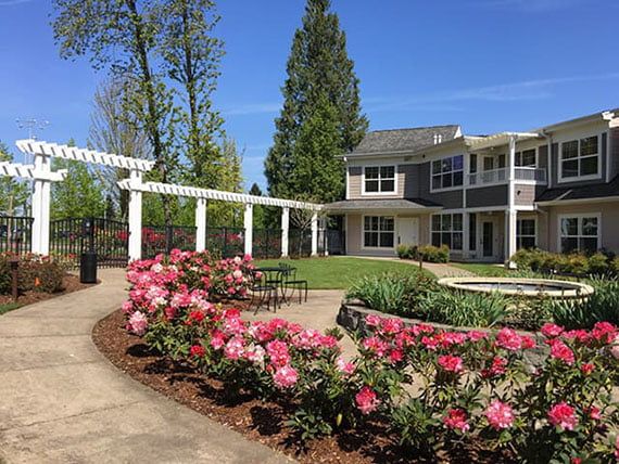 A beautifully landscaped garden with blooming flowers in front of a two-story building.