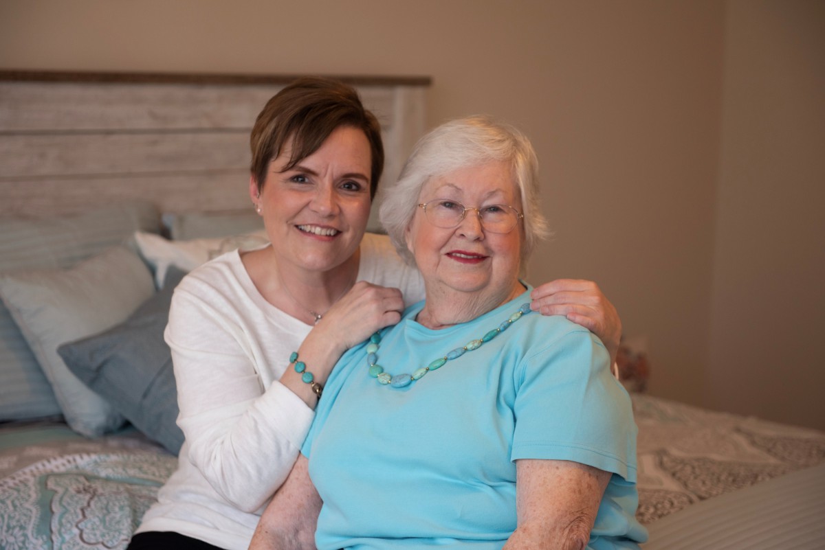 Two women smiling and posing together indoors.