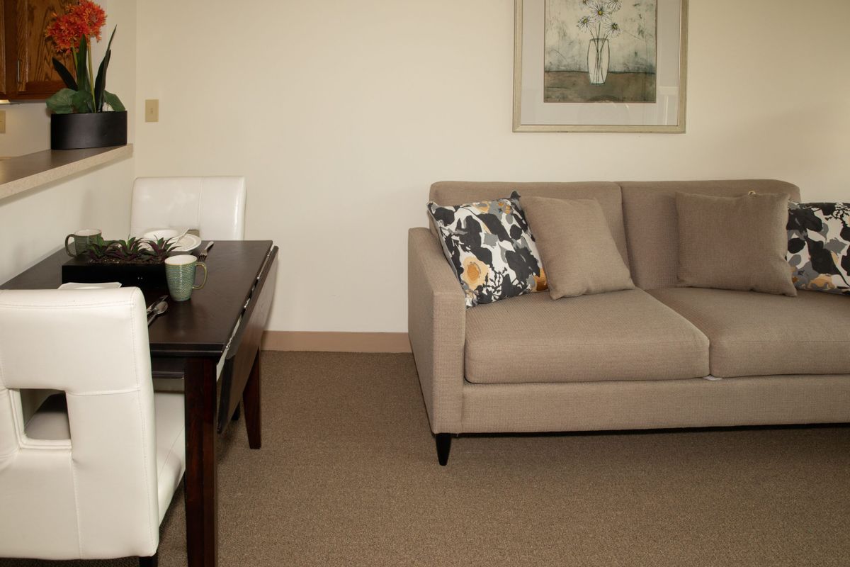 A cozy living room with a beige sofa, decorative pillow, and artwork on the wall.