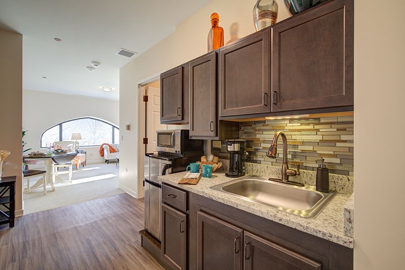 A contemporary kitchen featuring dark wood cabinets, a stone backsplash, and modern appliances.