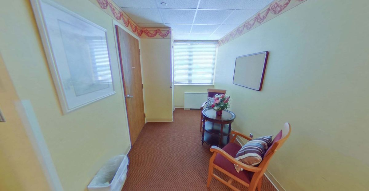 A well-lit waiting area with comfortable chairs and a small table by the window.