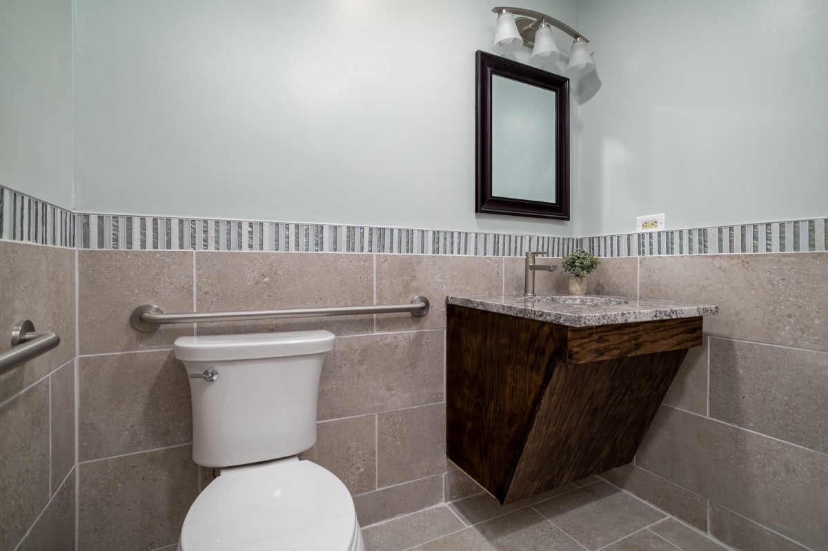 A modern bathroom featuring a sleek sink and mirror, complemented by tiled walls and flooring.