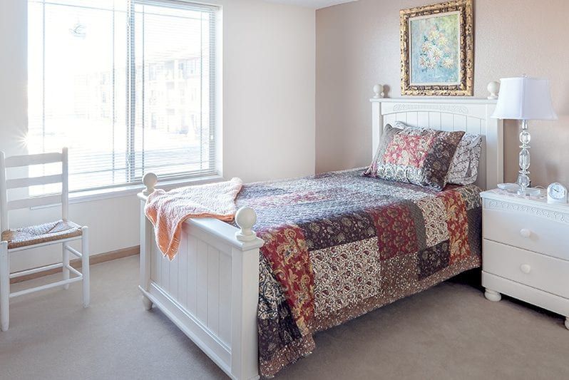 A cozy bedroom with a single bed adorned with a patchwork quilt, positioned near a large window that lets in natural light.