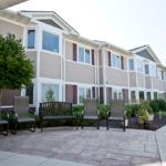 A modern residential building with outdoor seating and landscaped surroundings.