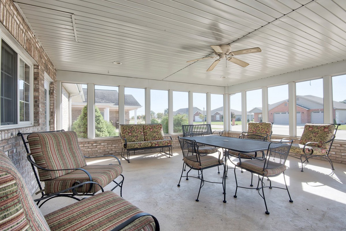 A bright sunroom with seating, a dining table, and large windows.