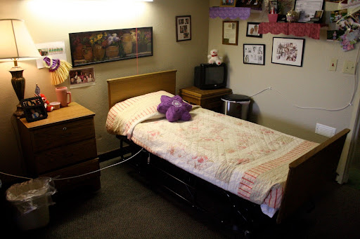 A cozy bedroom featuring a single bed with a purple stuffed animal, surrounded by personal touches and decor.