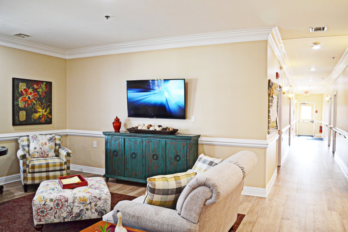 A cozy living room with a sofa, a wall-mounted television, and a teal cabinet.