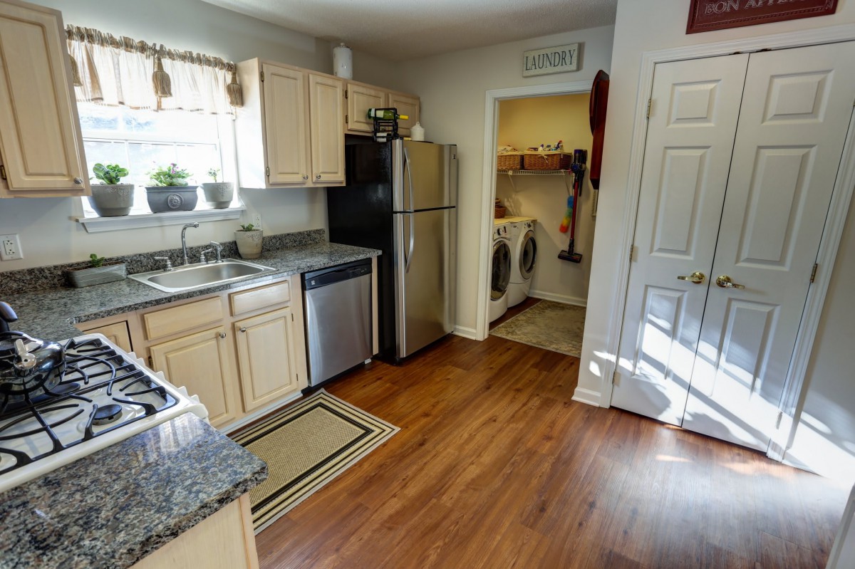 A cozy kitchen with wooden flooring and a connected laundry room.