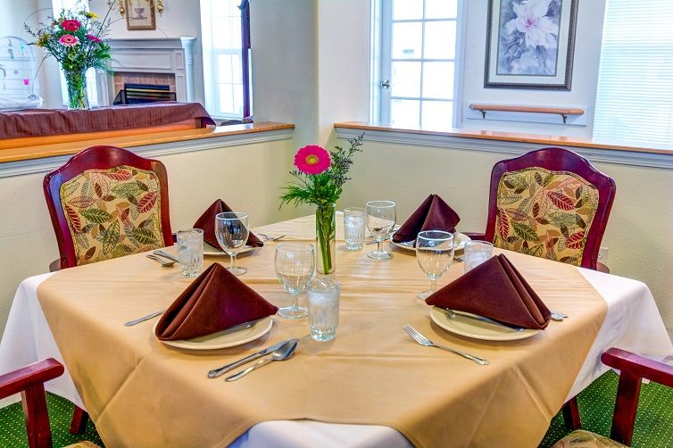 A neatly set dining table with folded napkins and a flower centerpiece in a cozy restaurant setting.