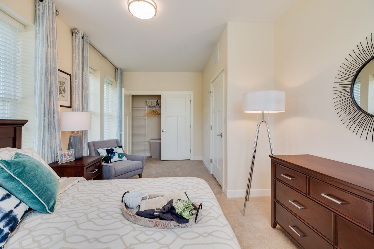 A cozy, well-lit bedroom featuring a bed, a dresser, and modern decor elements.