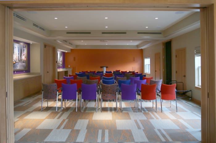 An empty conference room set up with colorful chairs facing a podium.