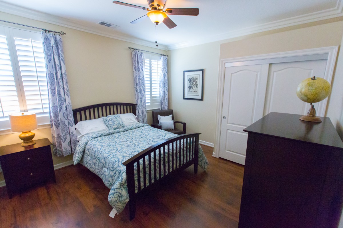 A cozy bedroom with wooden floors and a neatly made bed.