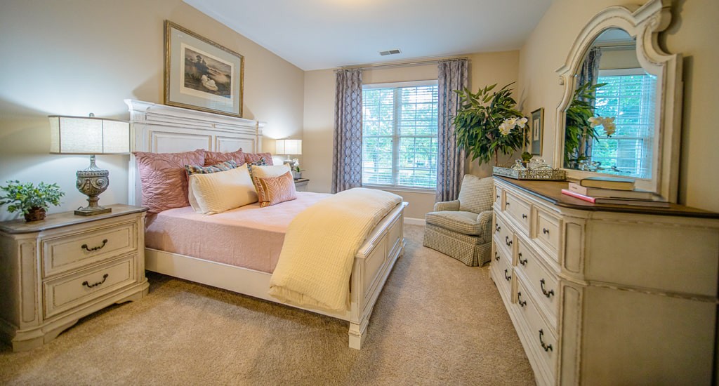 A cozy and well-decorated bedroom with a bed, dresser, and large window.