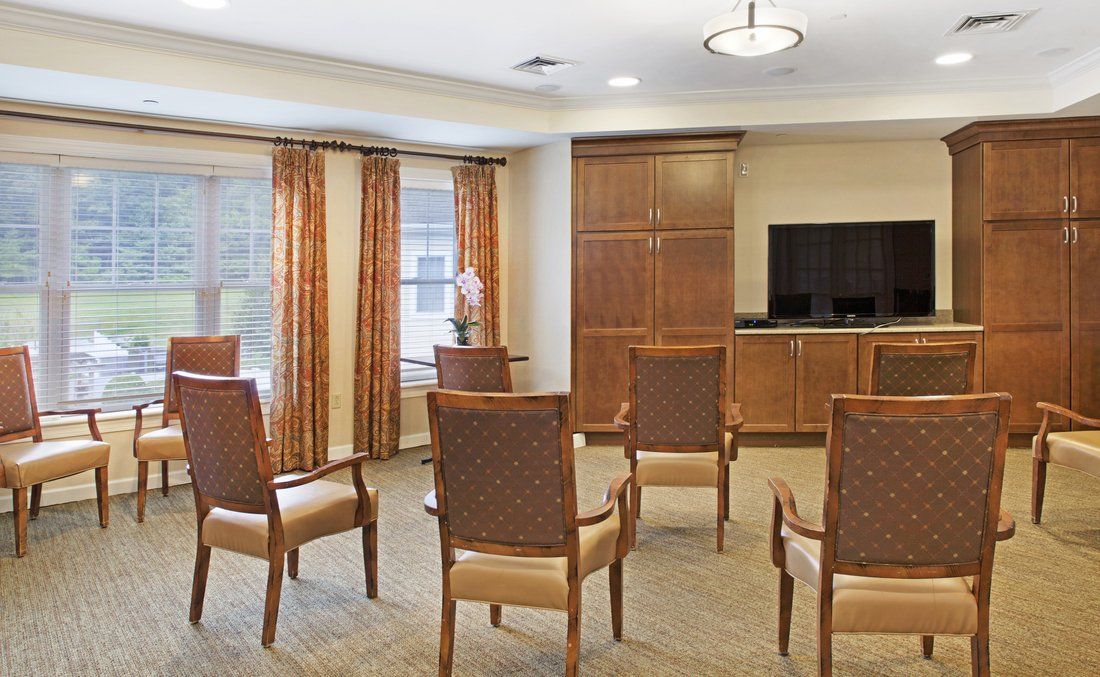 A neatly arranged meeting room with chairs facing a television.