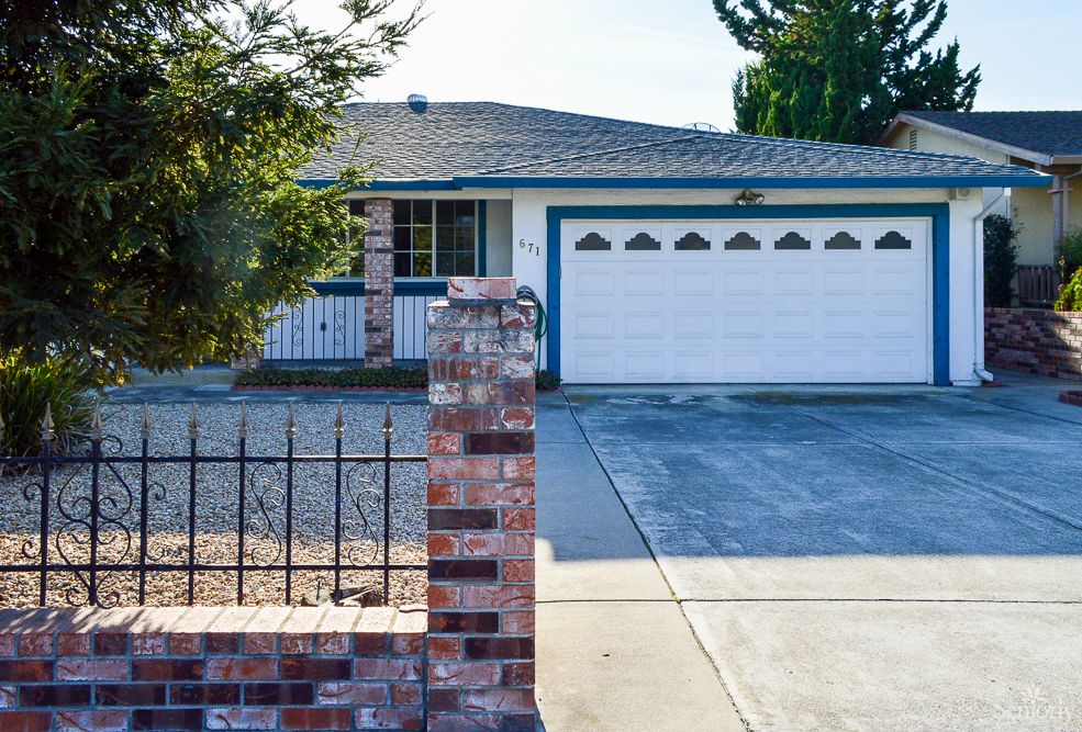 A suburban house with a two-car garage and brick fencing.