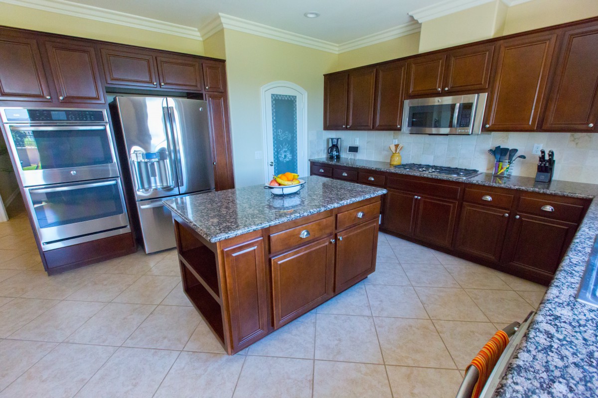 A modern kitchen with wooden cabinets, a central island, and stainless steel appliances.
