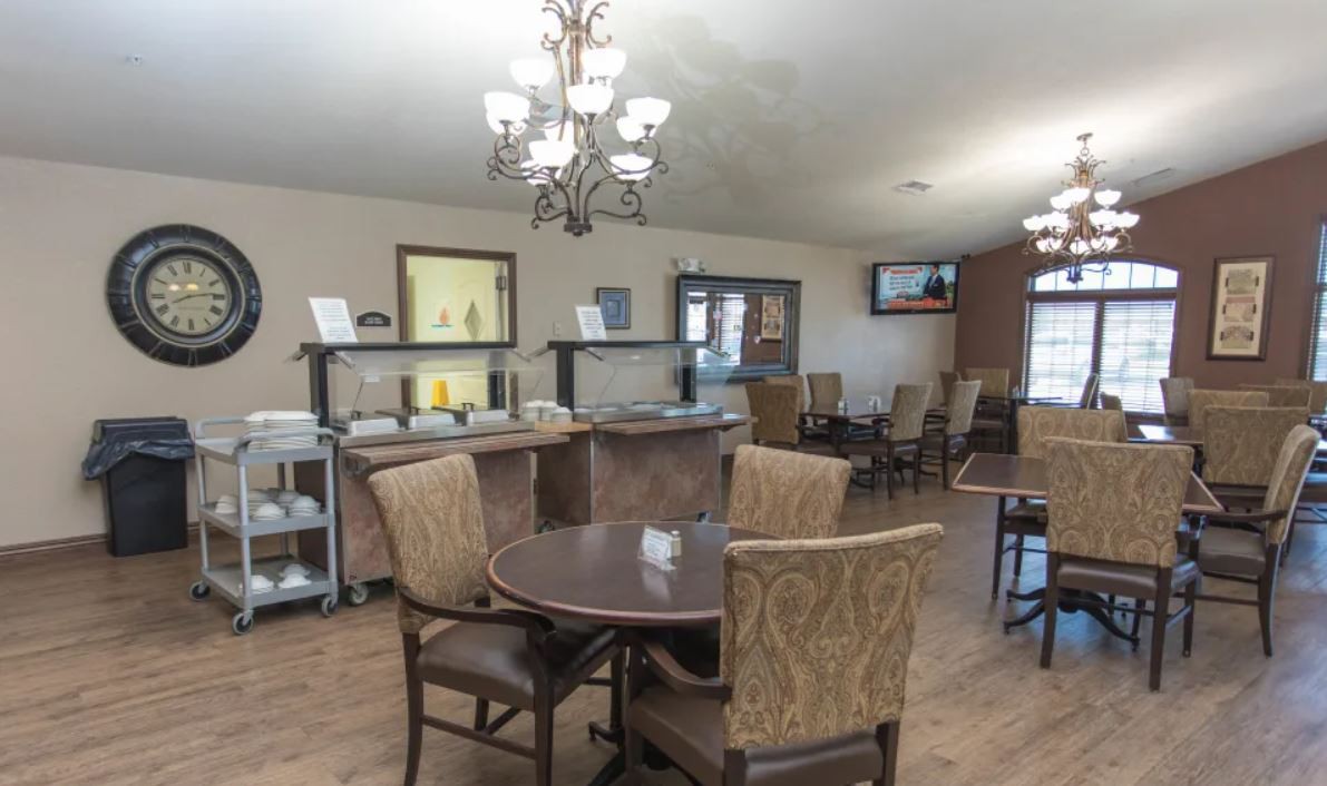 A cozy dining area with a chandelier and neatly arranged tables and chairs.