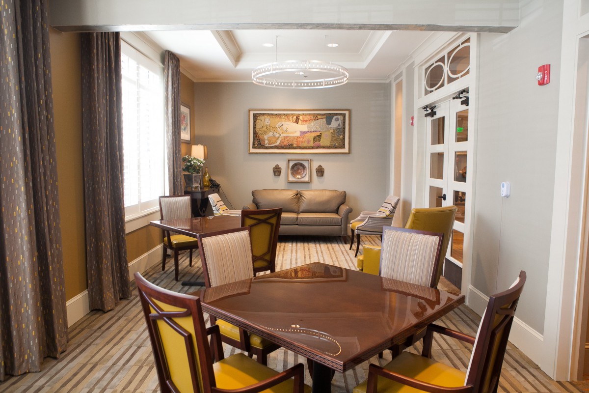A cozy living room with a sofa, chairs, and a table, featuring warm colors and elegant decor.