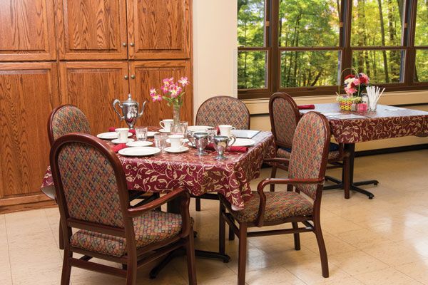 A cozy dining room table set for a meal, featuring elegant dishware and a floral centerpiece.