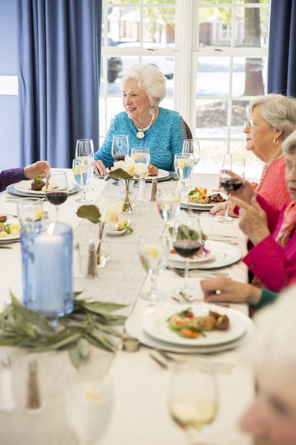 A group of elderly people enjoying a meal together at a beautifully set table.
