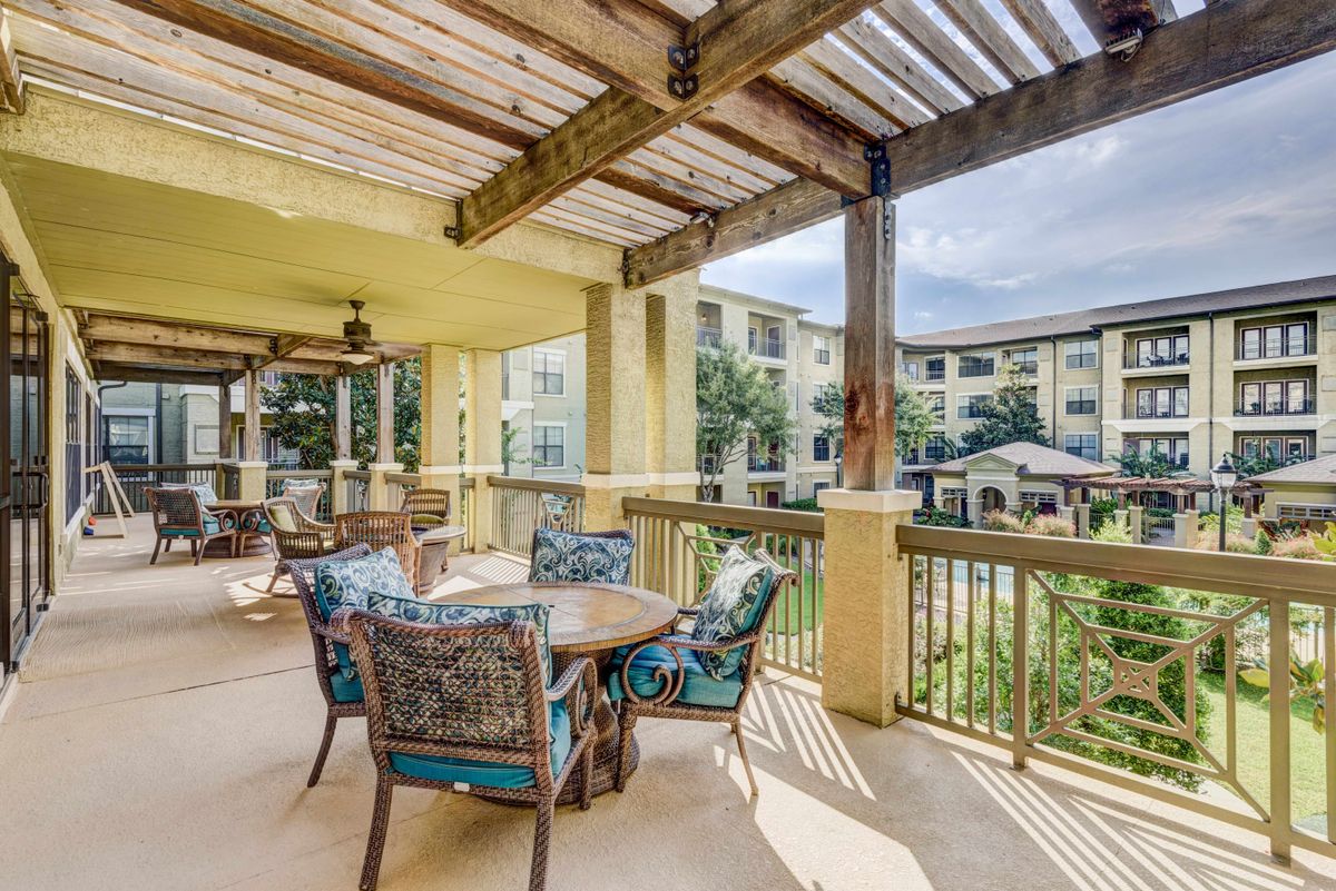 A cozy outdoor patio with comfortable seating and a pergola overlooking a well-maintained residential garden.