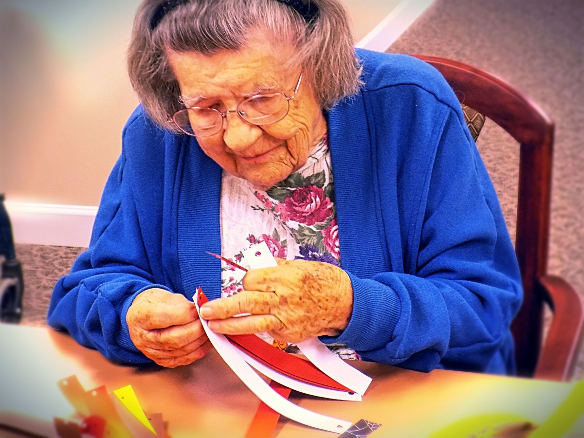 An elderly woman enjoying a crafting activity indoors.