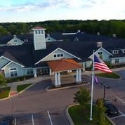 Aerial view of a large building with an American flag and parking lot.