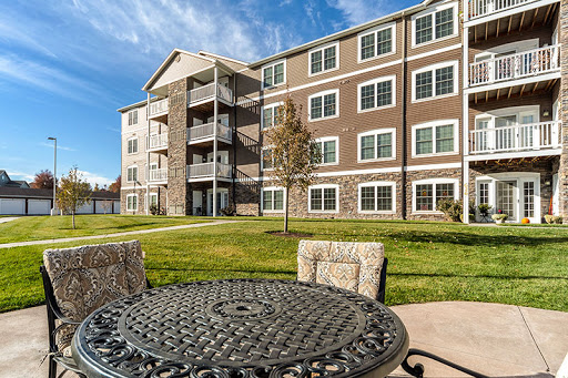 A modern apartment building with a well-maintained lawn and outdoor seating.
