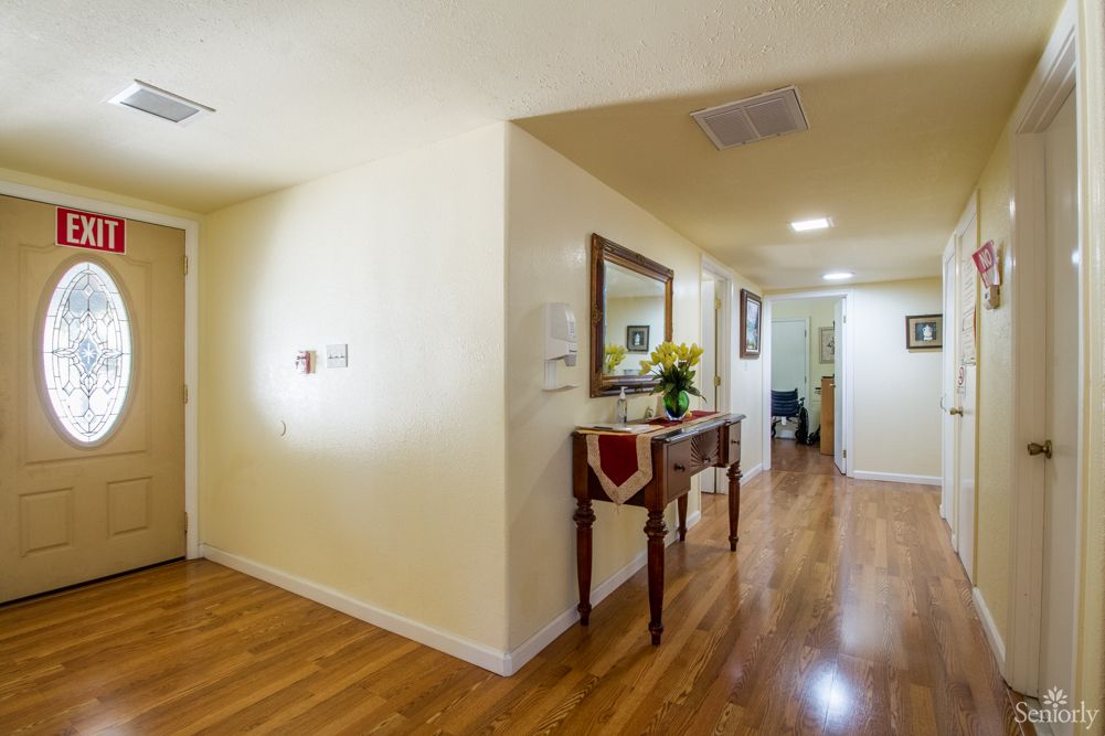 A well-lit hallway with wooden flooring, featuring a decorative table and mirror.