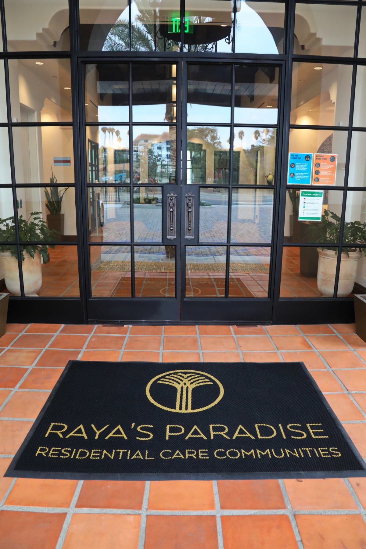 Entrance to a residential care community with a welcoming mat labeled 'Raya's Paradise'.