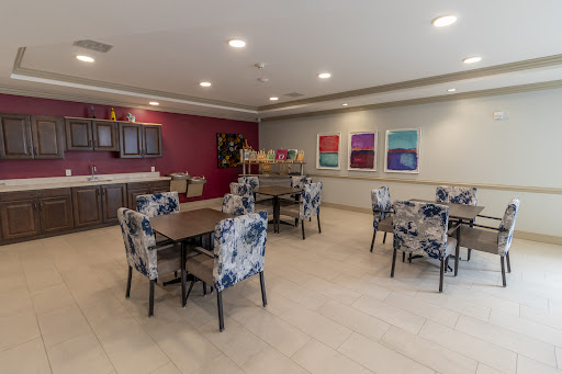 A modern dining area featuring floral-patterned chairs, a kitchen countertop, and colorful artwork on the walls.