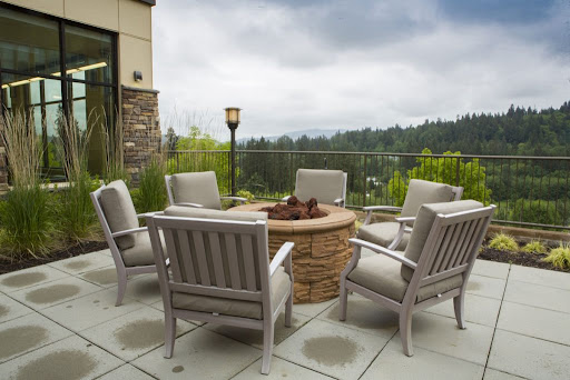 A cozy outdoor patio setup featuring comfortable chairs around a fire pit, with a scenic view of the surrounding landscape.
