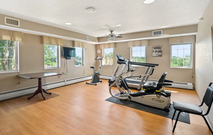 A well-lit exercise room with fitness equipment, including a treadmill and stationary bike.