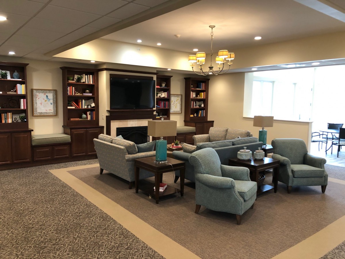 A cozy living room with a seating area, bookshelves, and a television.