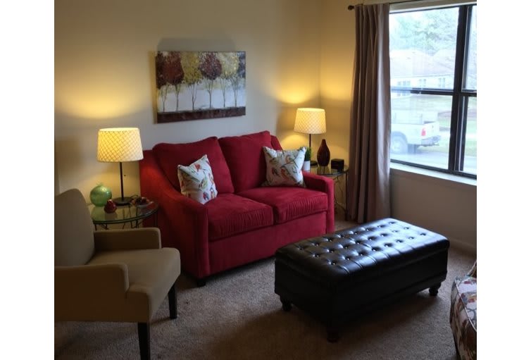 A cozy living room with a red sofa, armchair, and a large window.