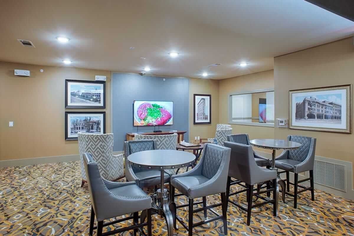 A modern dining area with tables and chairs, decorated with artwork on the walls and featuring a patterned carpet.