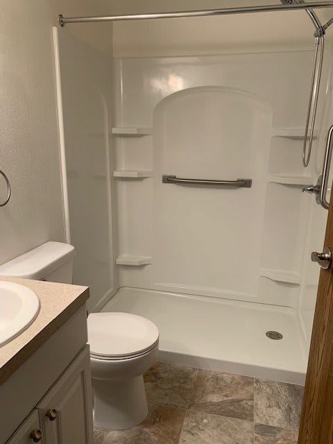 A clean bathroom with a shower, toilet, and sink.