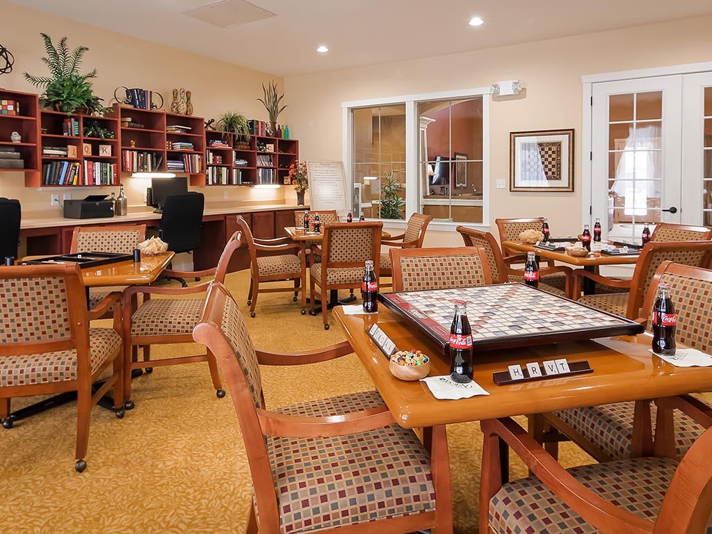 A cozy game room with tables set for board games and library shelves in the background.