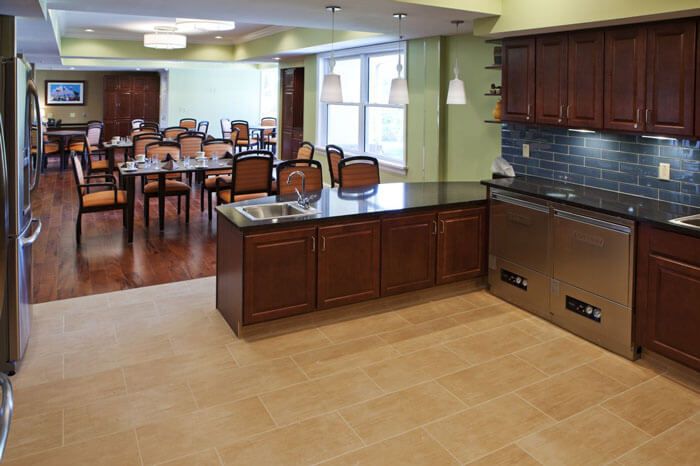 A modern kitchen and dining area with wooden cabinets and elegant lighting.