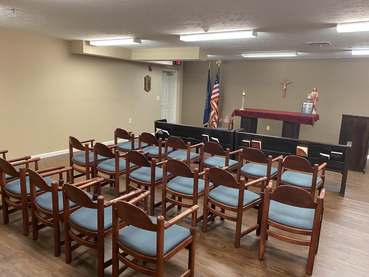 A small chapel with wooden chairs and an altar in the background.