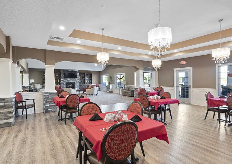 A spacious dining area with red tablecloths and elegant chandeliers.