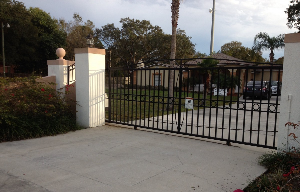 A residential driveway with a black metal gate and view of the garden.