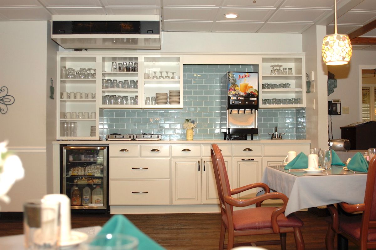 A cozy kitchen and dining area with neatly arranged cabinets, a beverage dispenser, and a table set for dining.