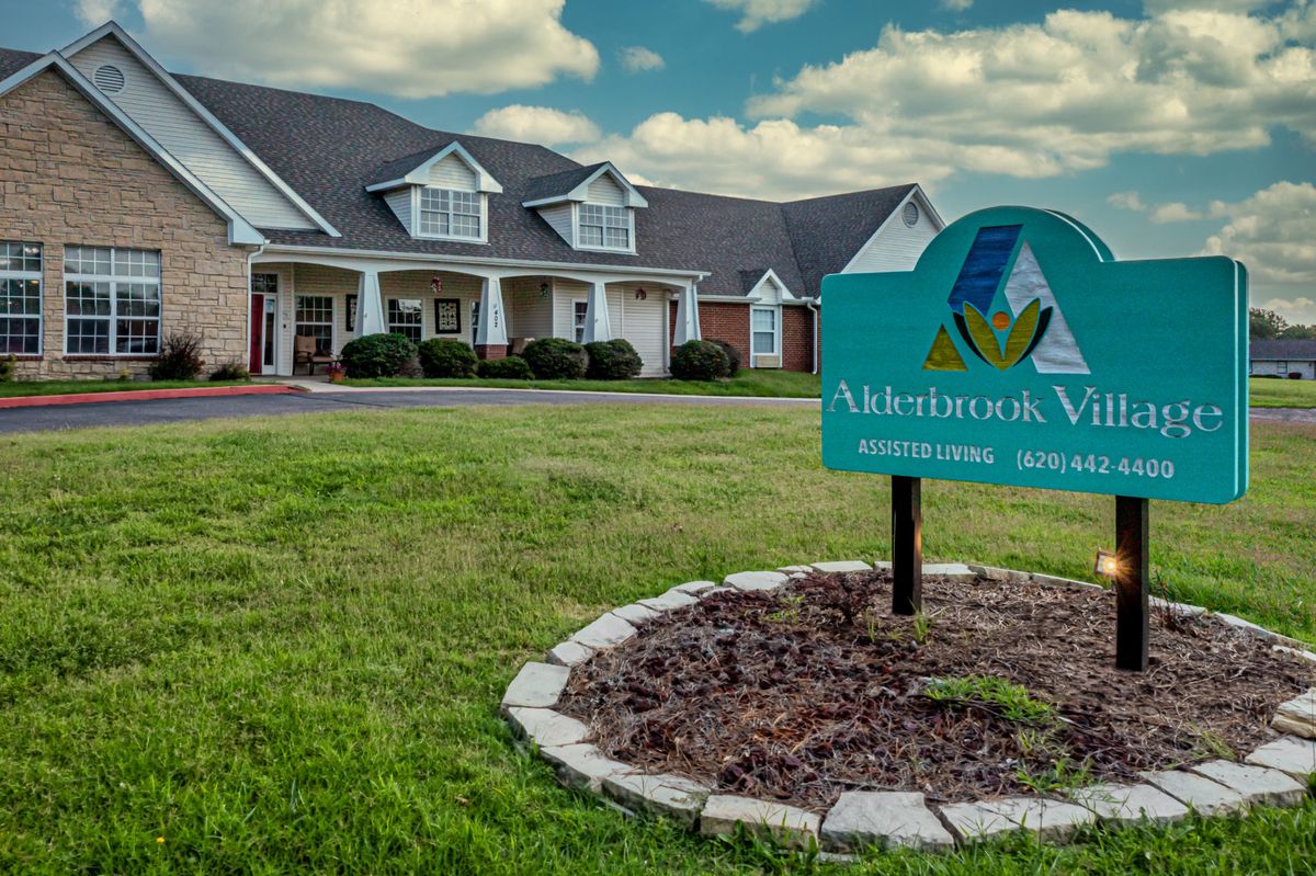 A building with a sign reading 'Memory Care' situated on a well-maintained lawn under a cloudy sky.